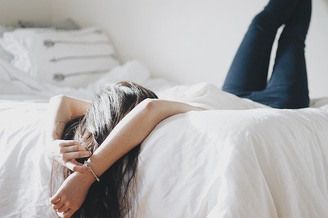 Vrouw ligt ontspannen op bed zonder stress